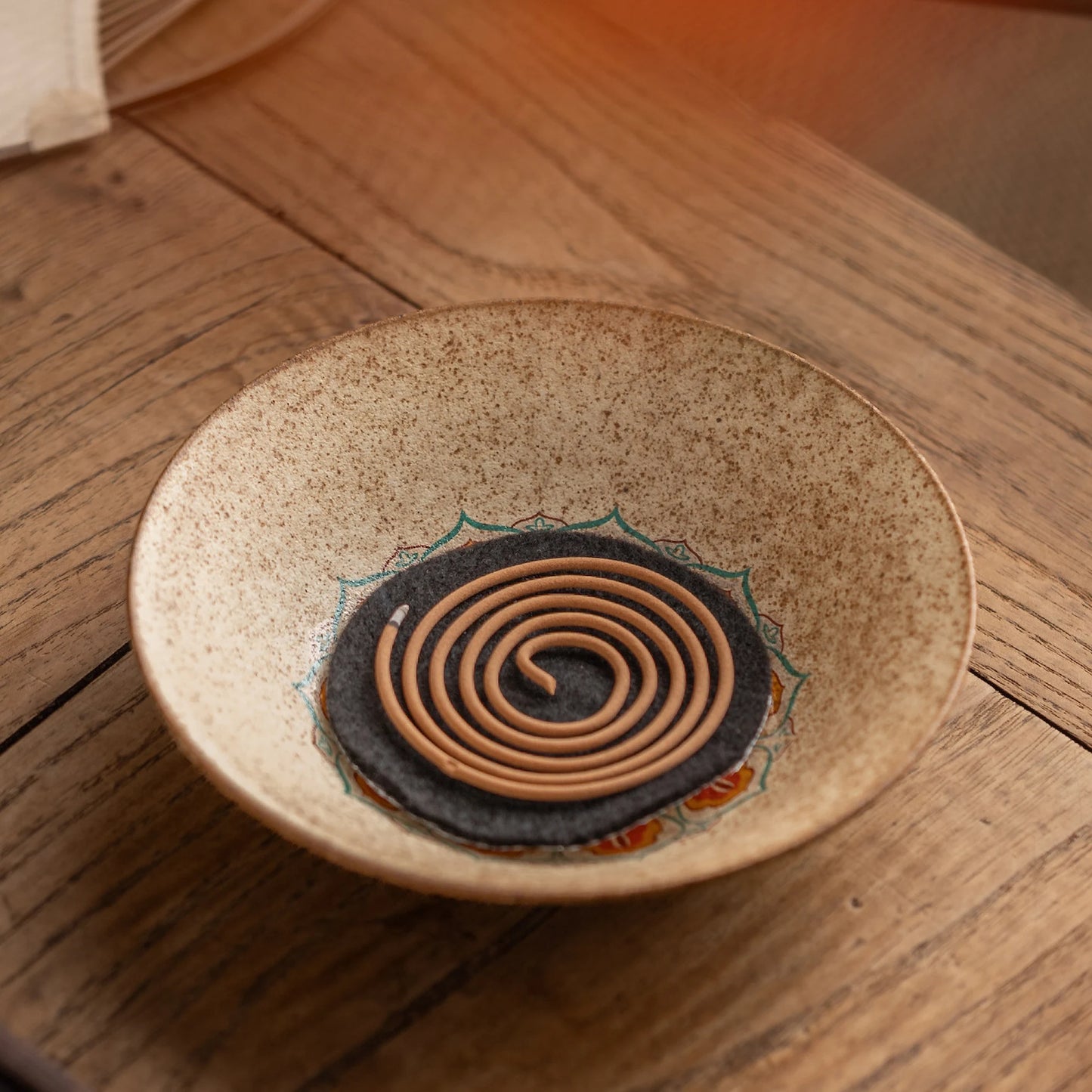 Vintage ceramic incense dish with fireproof mat holding a burning spiral coil incense, retro aromatherapy diffuser