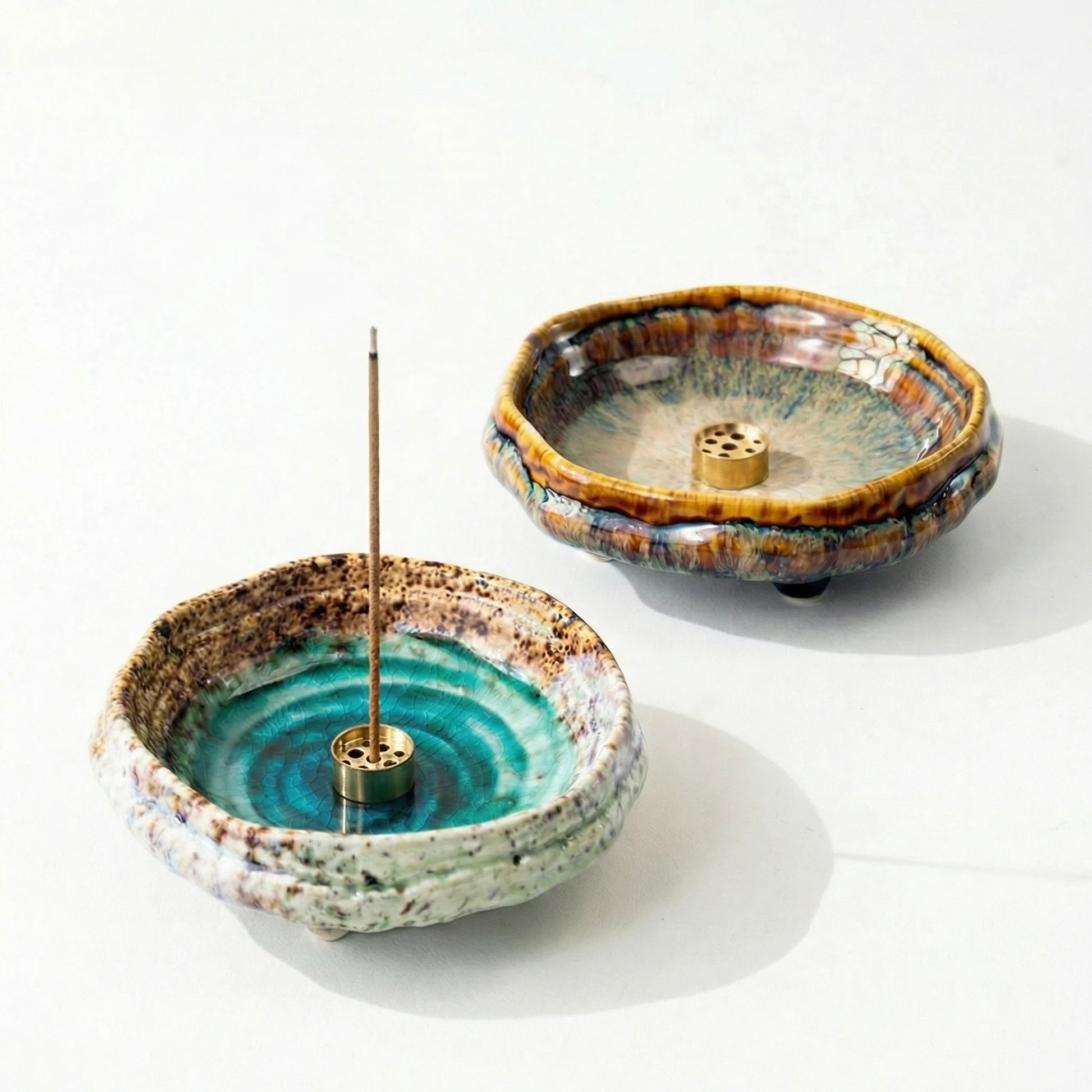 Collection of handmade wabi-sabi ceramic incense holders in emerald green and amber brown with ice-crack glaze finish