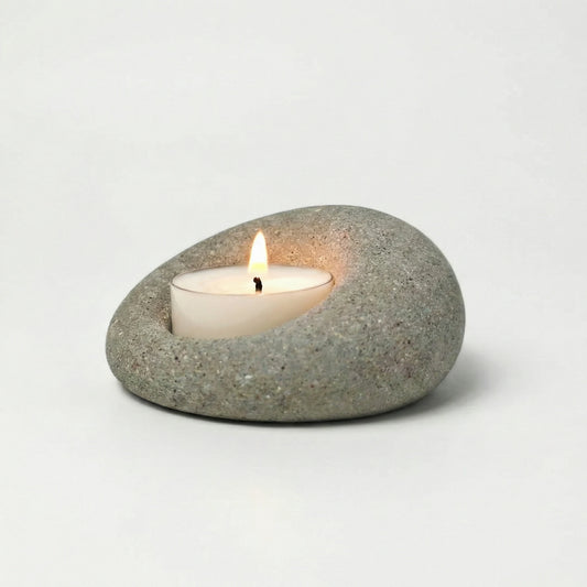 Minimalist natural stone tealight holder with a lit candle, wabi-sabi home decor accessory on a white background