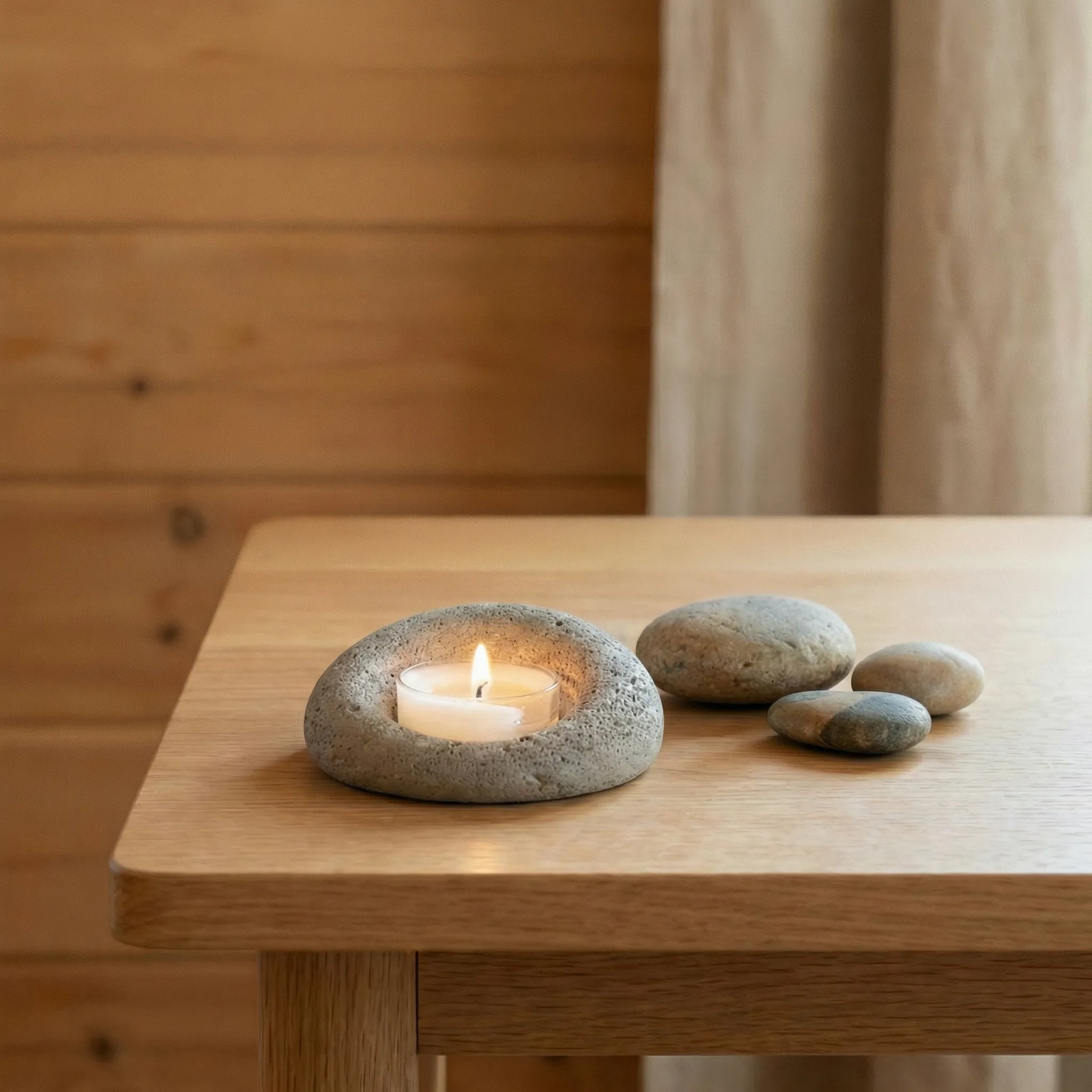 Handcrafted stone votive holder on a light wood desk, zen-inspired interior styling with natural elements.