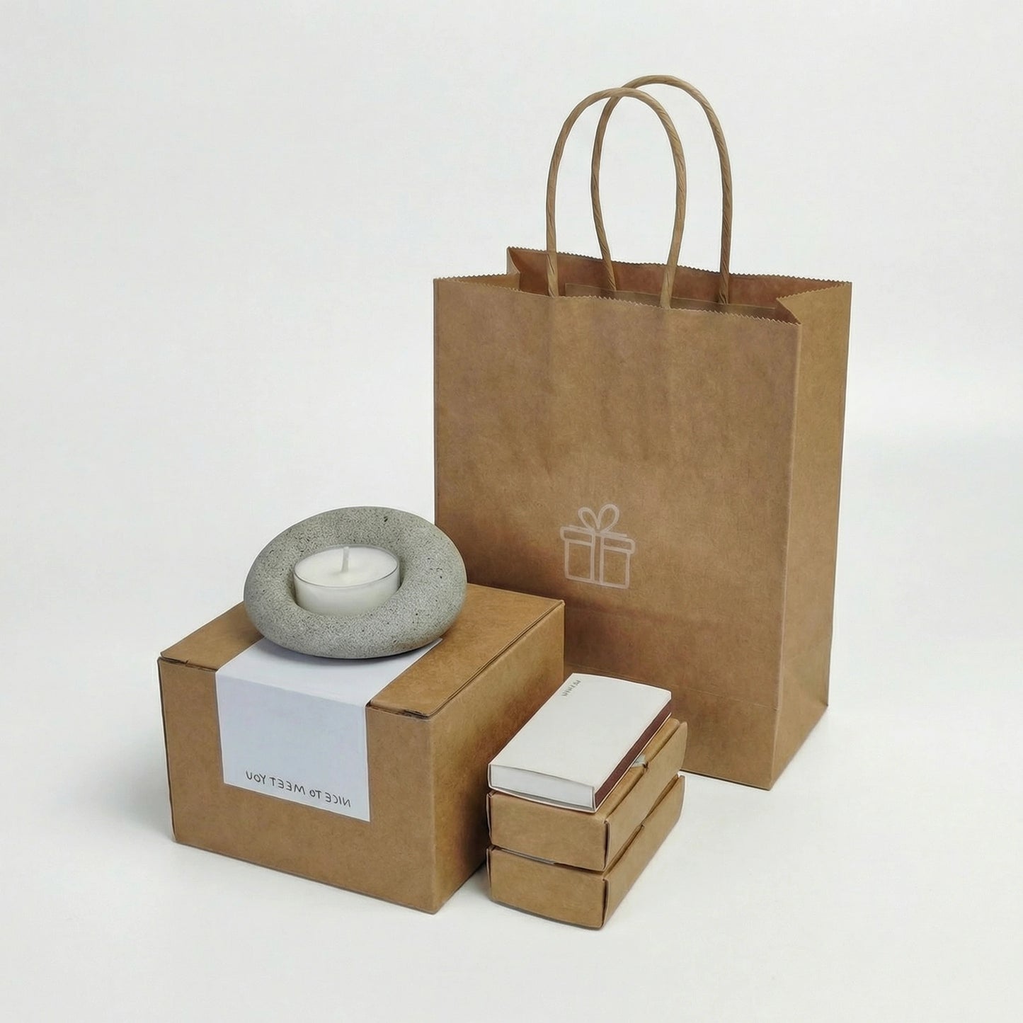 Wabi-sabi style gift set with a natural grey stone tealight holder atop a sustainable kraft paper gift box.