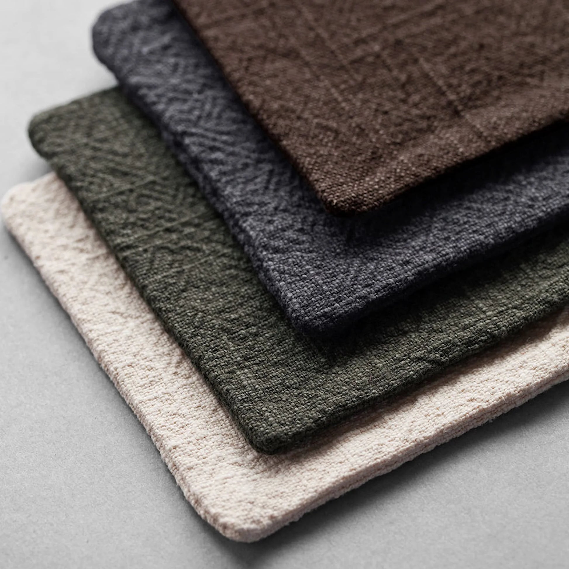 Close-up of stacked handmade fabric coasters in neutral tones, highlighting the premium cotton-linen weave and textured surface