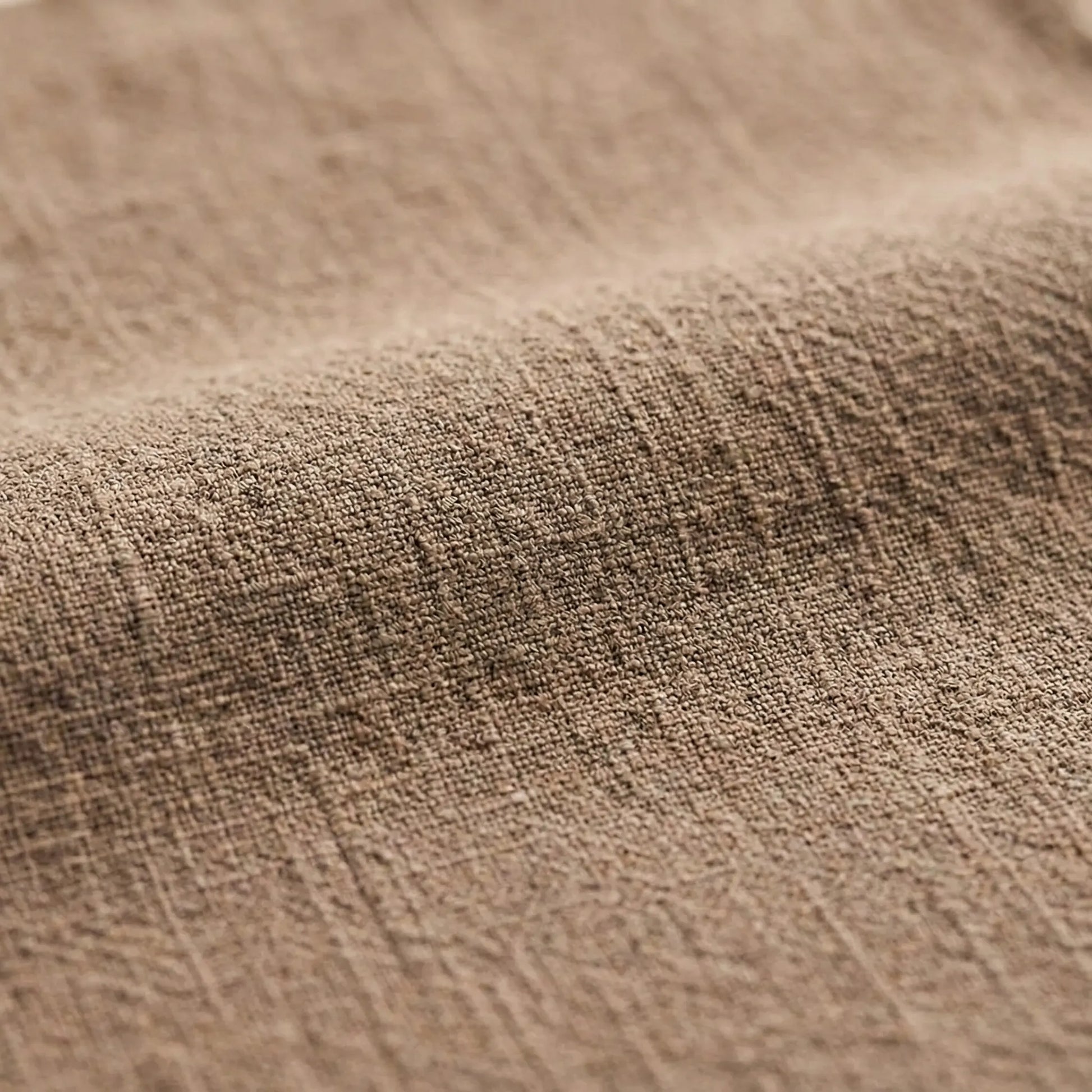 Macro view of a natural oatmeal-colored cotton linen fabric, emphasizing the soft ripples and anti-static woven material