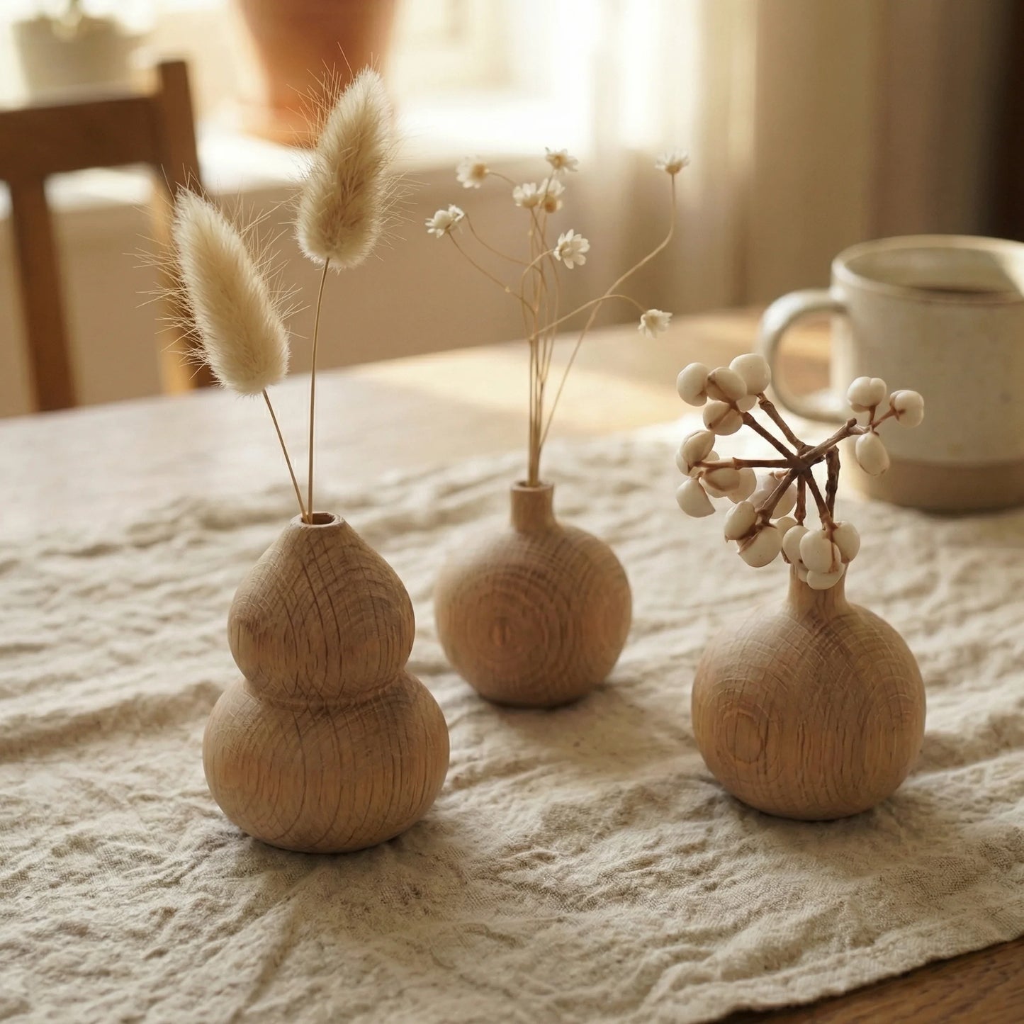 Minimalist round white oak wood bud vase holding a single branch of white berries.