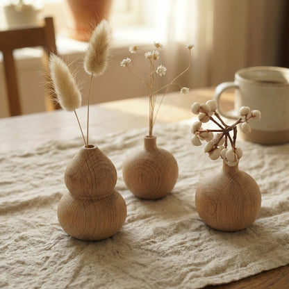 Minimalist round white oak wood bud vase holding a single branch of white berries.