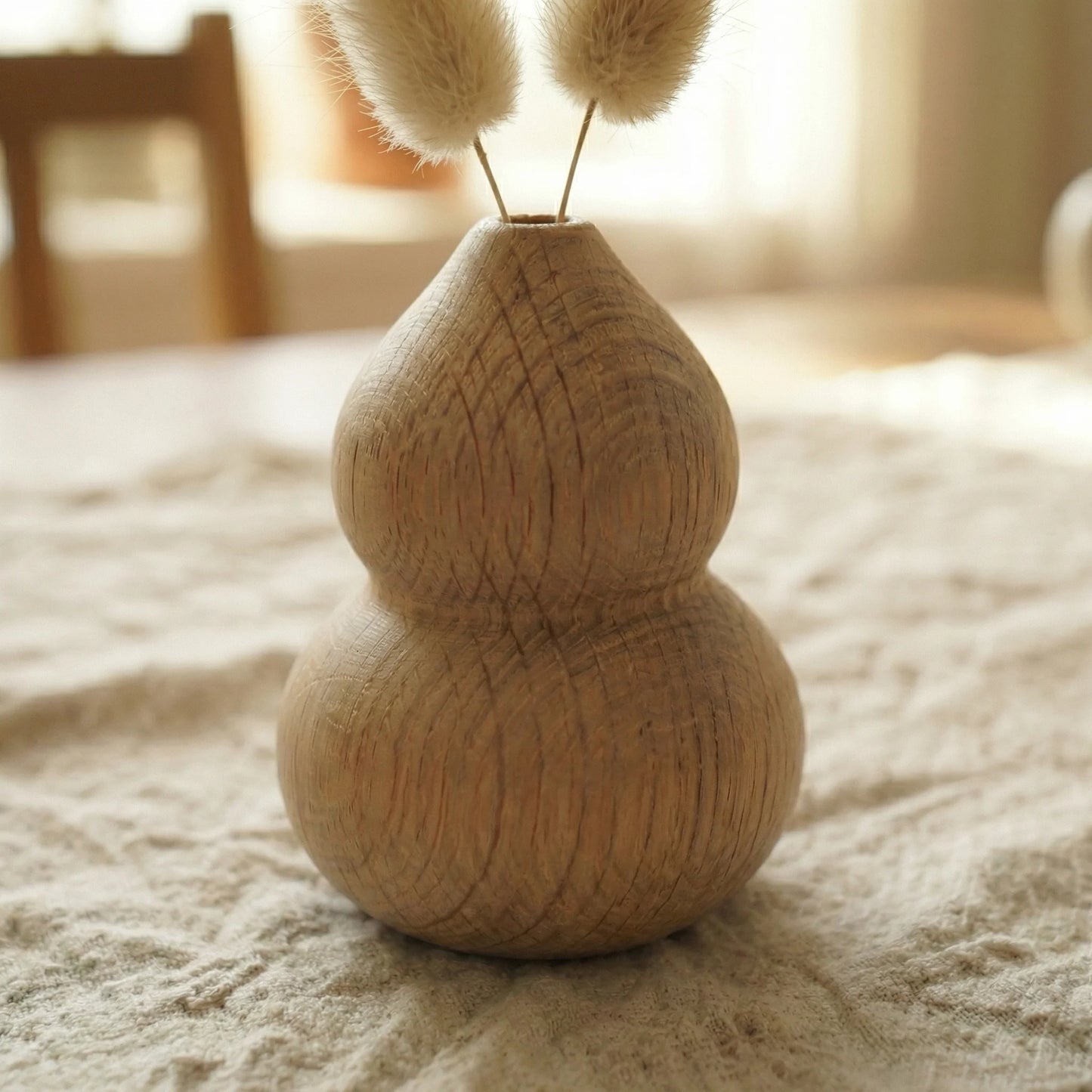 Minimalist round white oak wood bud vase holding a single branch of white berries.